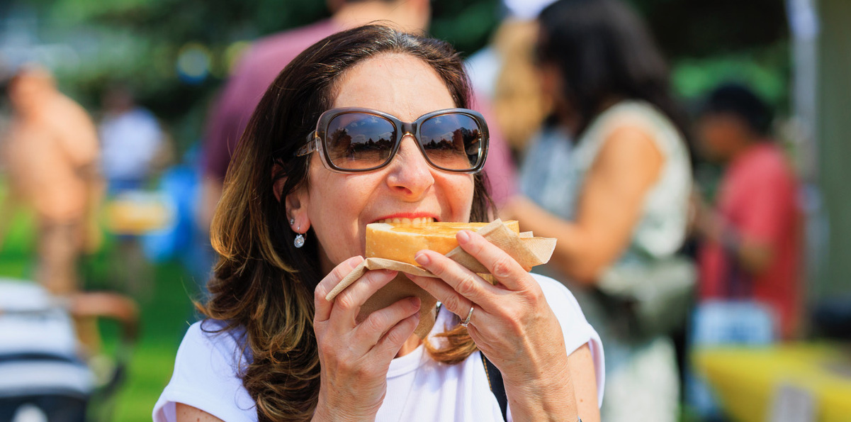 A woman wearing sunglasses eating a hot dog